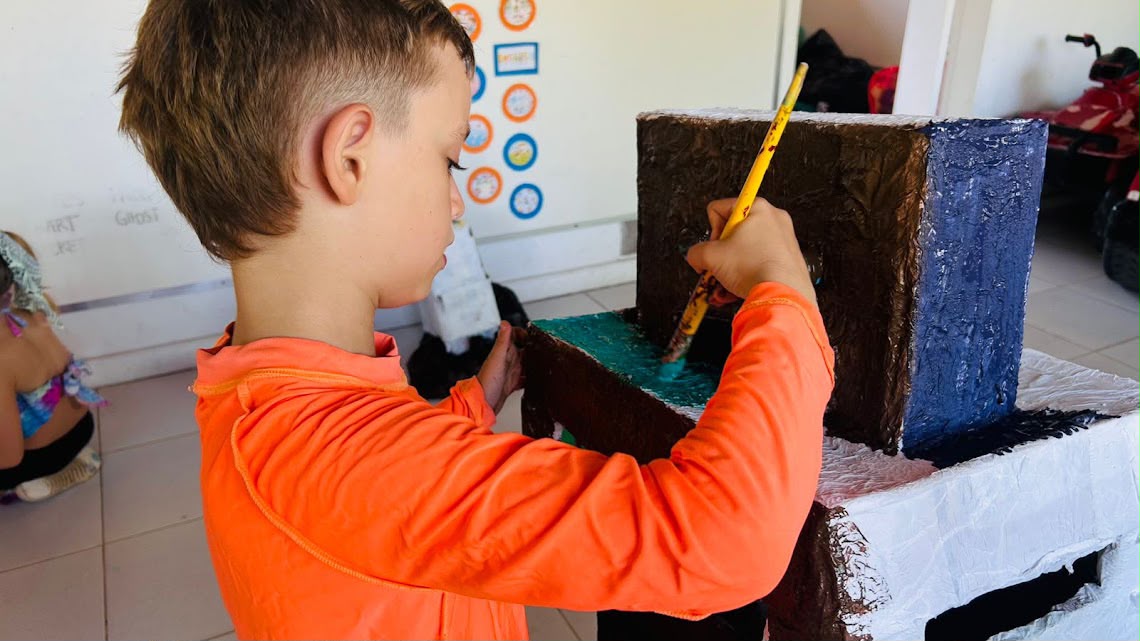 Criança pintando uma estrutura durante atividade no Ateliê de Artes