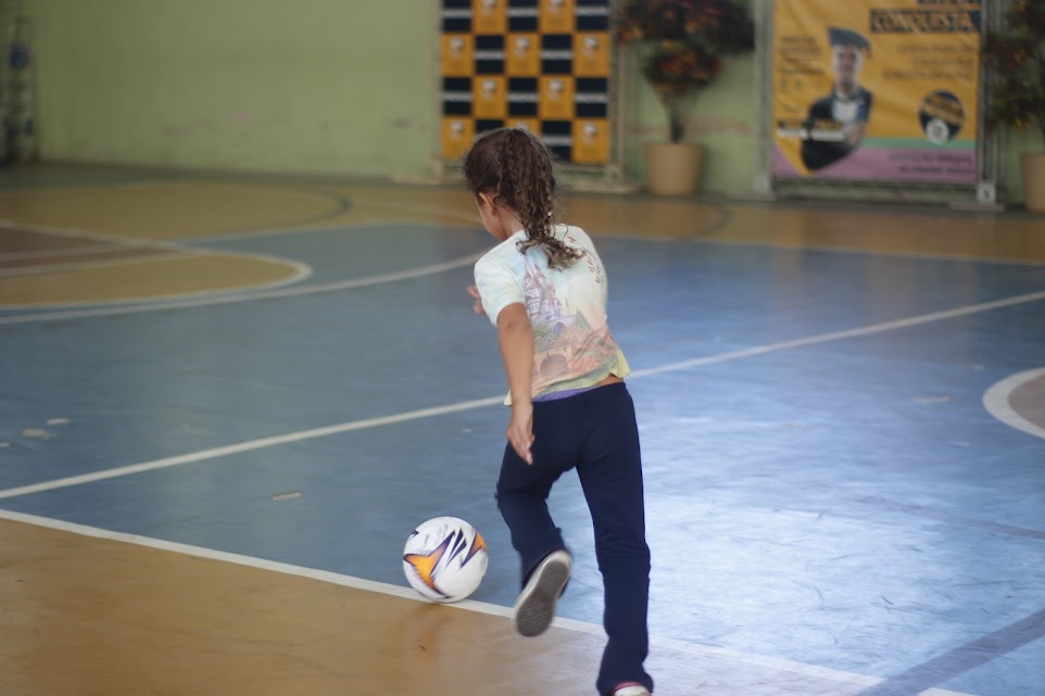 Criança participando de atividade de futebol em quadra
